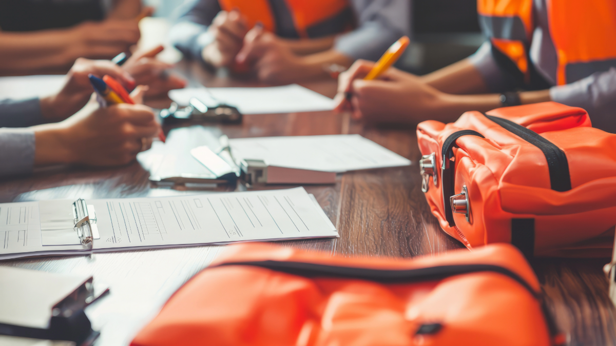Emergency preparedness meeting with hands and emergency kits on the table